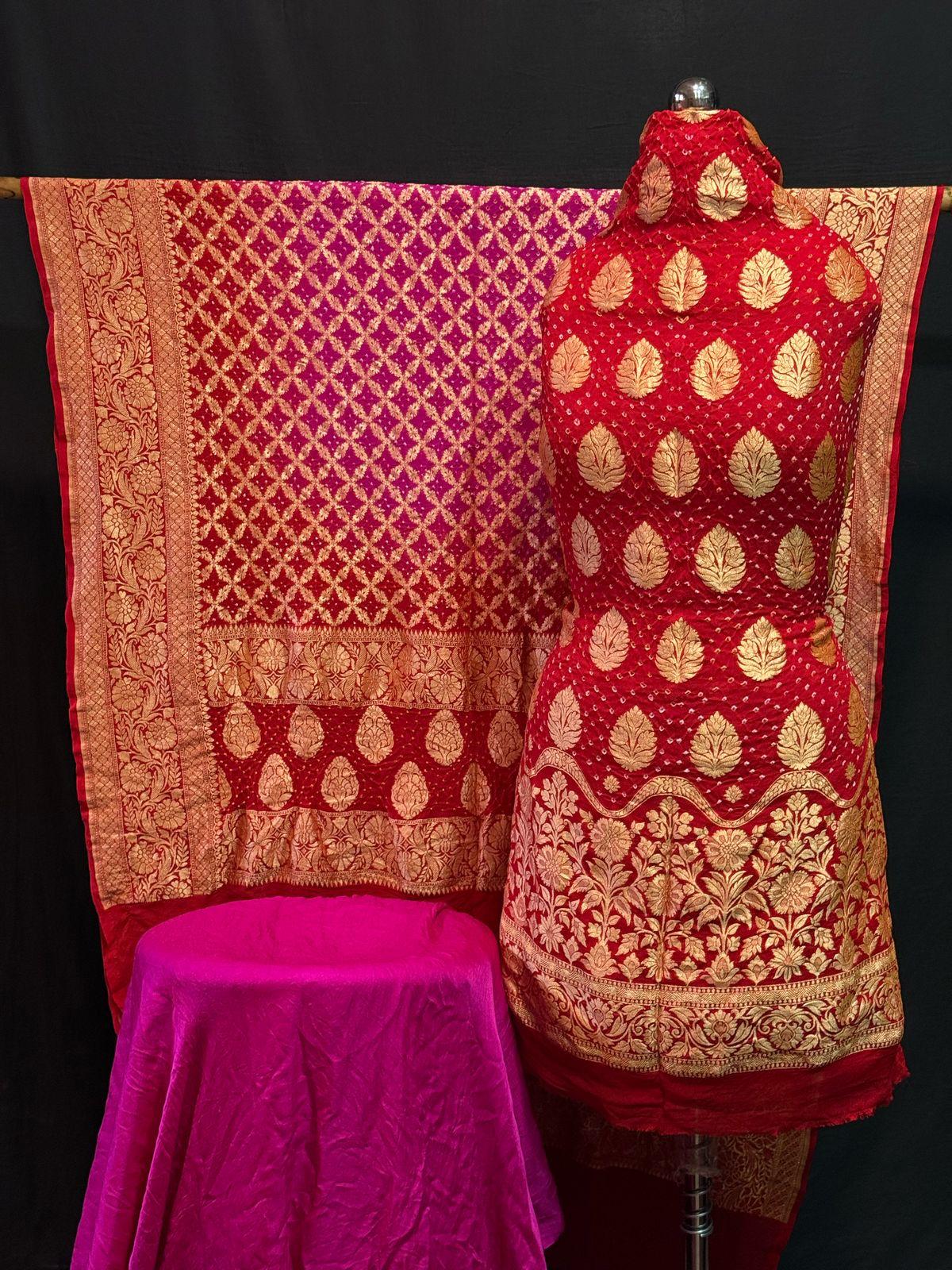 Red Banarasi saree with golden zari work and pink pallu displayed on mannequin with velvet base